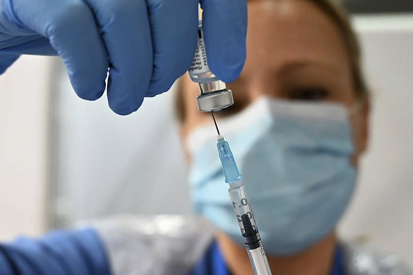 A worker in Scotland with a dose of the Pfizer COVID-19 vaccine.