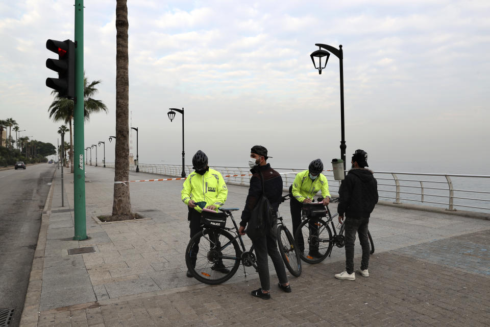 Police issue fines to civilians violating health safety measures on the waterfront promenade as the county starts a new, three-week lockdown amid a record post-holiday surge of new coronavirus cases that has overwhelmed the national health sector in Beirut, Lebanon, Thursday, Jan. 7, 2021. (AP Photo/Bilal Hussein)
