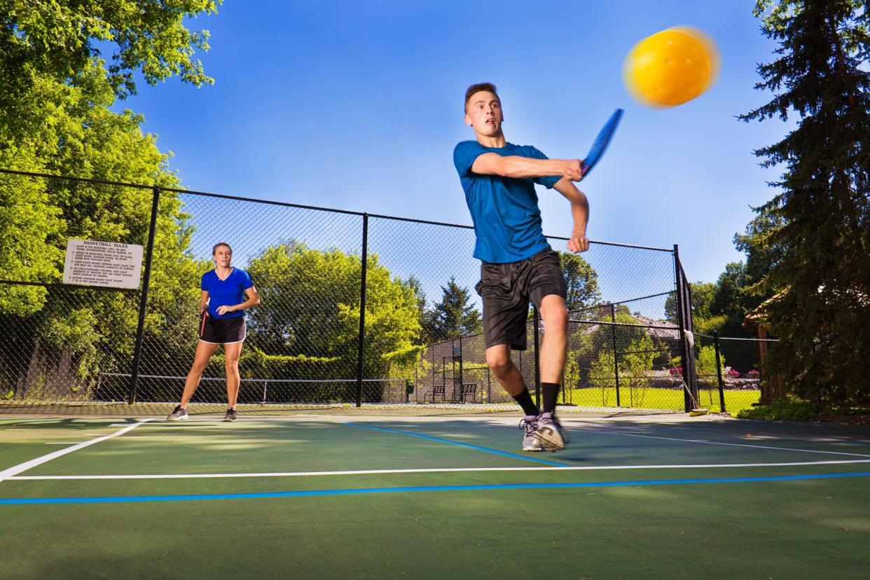 Two young teen boy and girl playing pickle ball in a court. Photographed in horizontal format in USA.