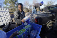 FILE - In this Feb. 22, 2021, file photo, Madonna Manor maintenance supervisor Lamar Jackson left, stacks bottled water brought by Mac Epps of Mississippi Move, as part of the supply efforts by city councilman and State Rep. De'Keither Stamps to a senior residence in west Jackson, Miss. The snow and ice that crippled some states across the South has melted. But it has exposed the fragility of aging waterworks that experts have been warning about for years. Cities across Texas, Tennessee, Louisiana and Mississippi are still grappling with outages that crippled health care facilities and forced families to wait in line for potable water. (AP Photo/Rogelio V. Solis)