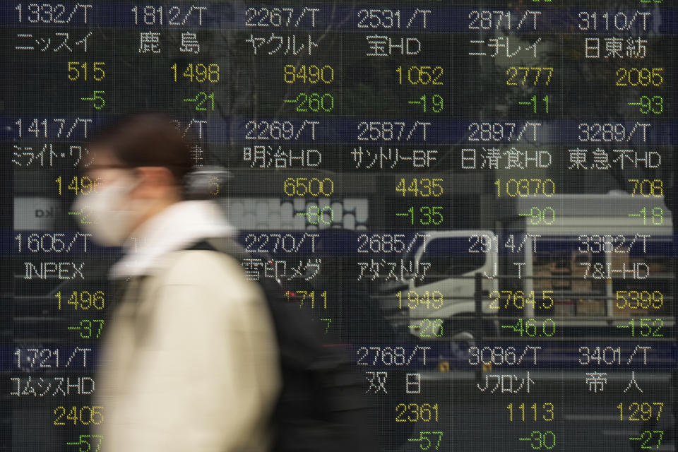 A woman walks by monitors showing Japanese companies' stock market prices at a securities firm in Tokyo, Friday, Dec. 2, 2022. Shares retreated in Asia on Friday after a mixed day on Wall Street as optimism over signs the Federal Reserve may temper its aggressive interest rate hikes was replaced by worries the economy might be headed for a recession. (AP Photo/Hiro Komae)