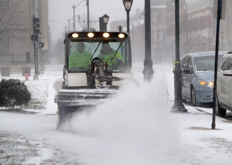 City workers remove snow on the sidewalk along Monroe Street in front of the Municipal Center West building Thursday Dec. 22, 2022.