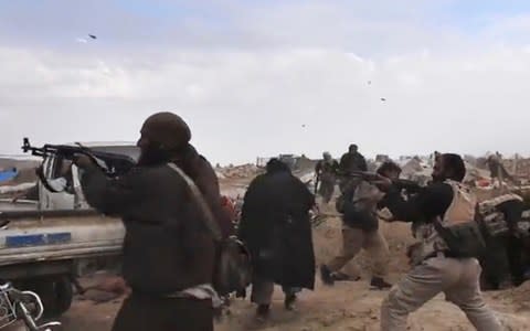 Video released by Isil from inside Baghouz shows fighters firing their weapons during clashes with the SDF - Credit: Amaq Agency