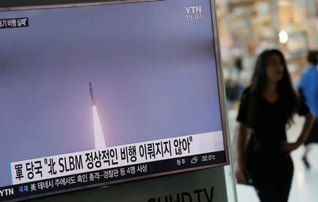 A passenger walks past a TV screen at a railway station in Seoul, South Korea, broadcasting a news report on North Korea's submarine-launched ballistic missile fired from North Korea's east coast port of Sinpo July 9, 2016. REUTERS/Kim Hong-Ji