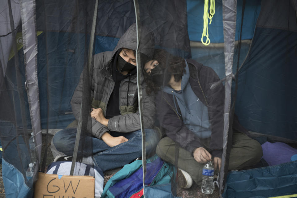 Estudiantes que protestan contra la guerra entre Israel y Hamás en la Universidad George Washington se sientan en una tienda de campaña para evitar la lluvia en Washington, sábado 27 de abril de 2024. Han surgido protestas y campamentos en los campus universitarios de todo el país para protestar contra la guerra. (AP Photo/Cliff Owen)