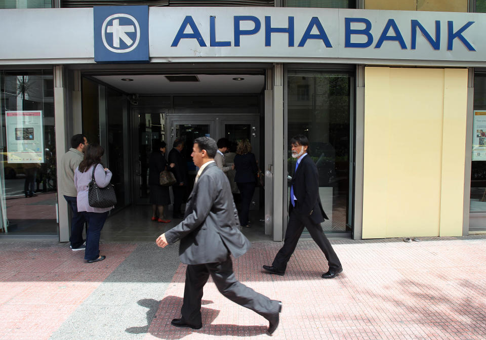 Pedestrians pass outside an Alpha Bank branch in Athens, Friday, April 20, 2012. Greek banks will publish their annual reports later Friday, which are expected to include severe losses resulting from their participation in the country's massive private debt writedown earlier this year. (AP Photo/Thanassis Stavrakis)