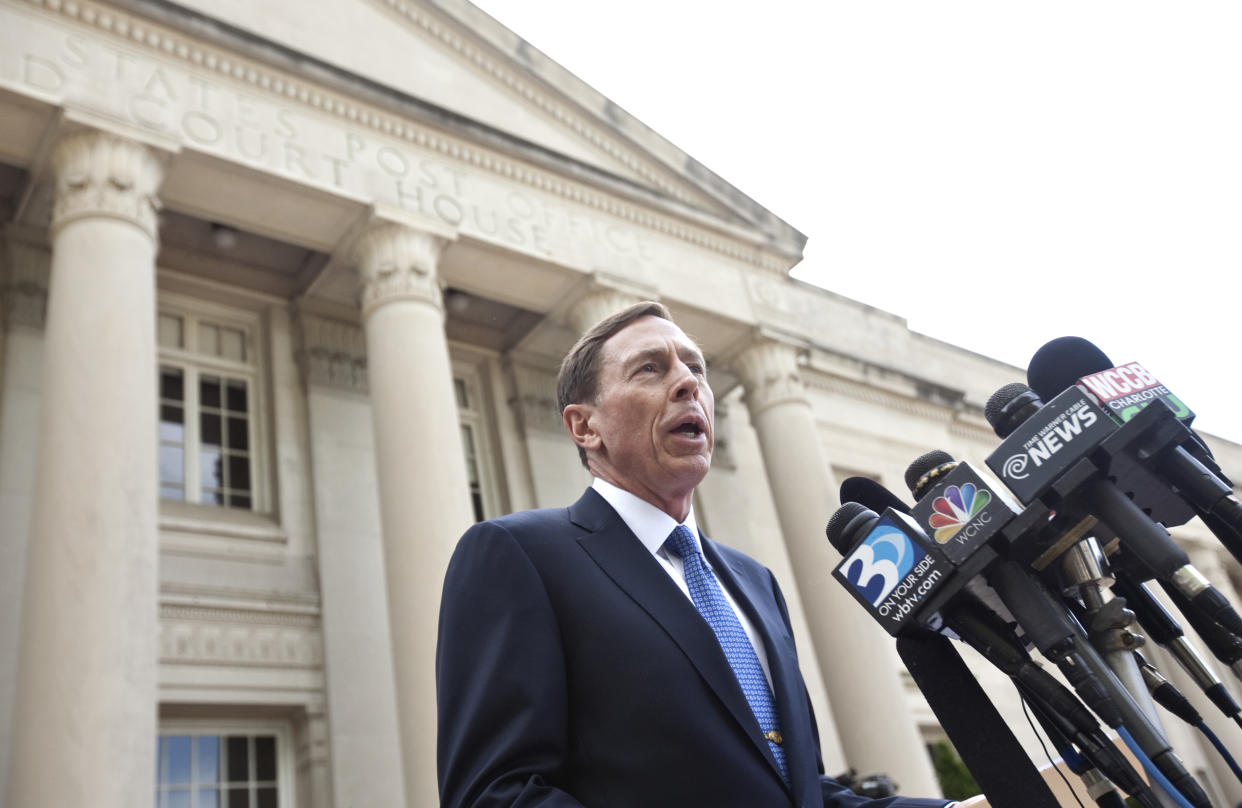 Gen. David Petraeus, under a colonnaded portico, gives a speech in front of a host of microphones.