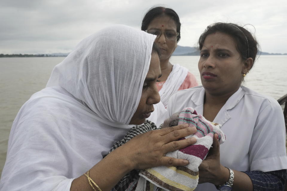 La comadrona Diluwara Begum susurra plegarias en los oídos de una bebé recién nacida a la que ayudó a nacer en un barco en el río Brahmaputra, en el estado nororiental indio de Assam, el miércoles 3 de julio de 2024. (AP Foto/Anupam Nath)