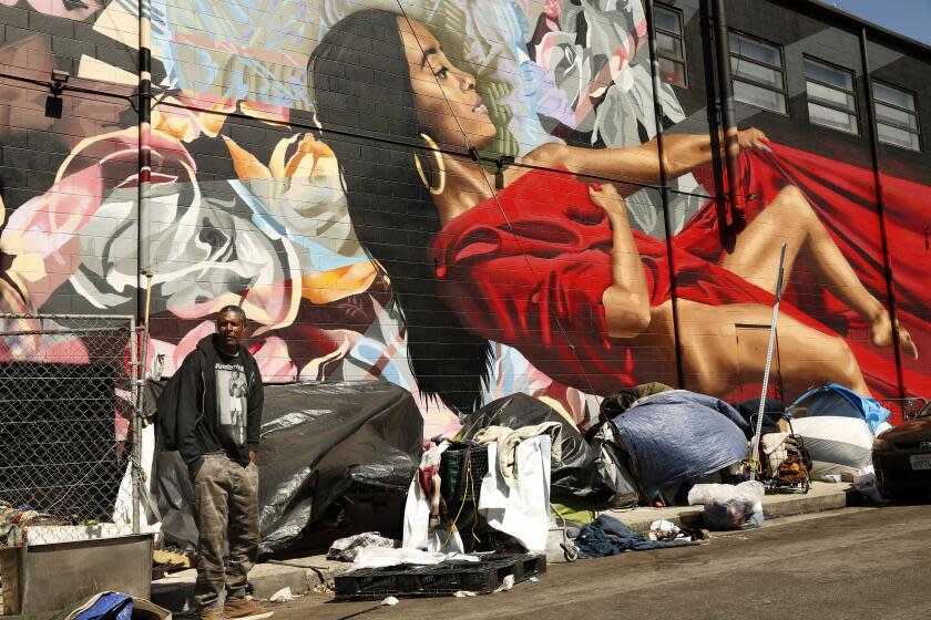 LOS ANGELES, CA - MARCH 26, 2020 - A homeless man by the name of Prince Thomas III stands in front of a row of tents and enclosures in skid row on Wilde Street in Los Angeles on March 26, 2020. A host of city and county officials attended a federal court hearing at the Alexandria Hotel that was presided by U.S. District Judge David Carter and U.S. District Judge Andre Birotte, Jr., to discuss possible immediate solutions to the Skid Row homeless crisis in light of the worsening coronavirus pandemic on March 26, 2020. Los Angeles Mayor Eric Garcetti and Los Angeles Chief of Police Michael Moore attended the hearing. (Genaro Molina / Los Angeles Times)