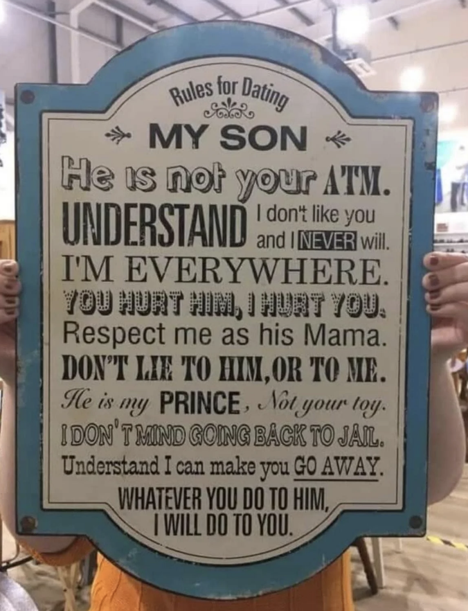 Person holding a sign with 'Rules for Dating My Son' including humorous threats about protecting him