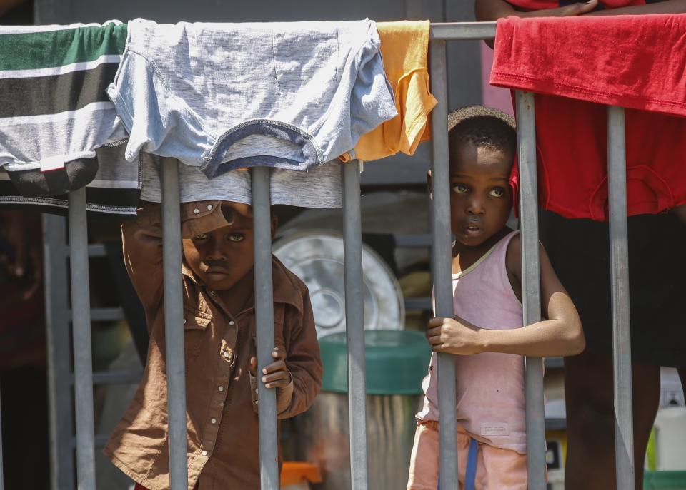 Children look through a fence at a shelter for families displaced by gang violence, in Port-au-Prince, Haiti, Wednesday, March 13, 2024. (AP Photo/Odelyn Joseph)