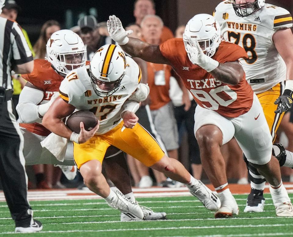 Texas defensive end Barryn Sorrell, left, sacks Wyoming quarterback Evan Svoboda as defensive lineman Byron Murphy II closes in Saturday at Royal-Memorial Stadium. Sorrell's first sack of the season helped the Longhorns pull away for a 31-10 win over the Cowboys.