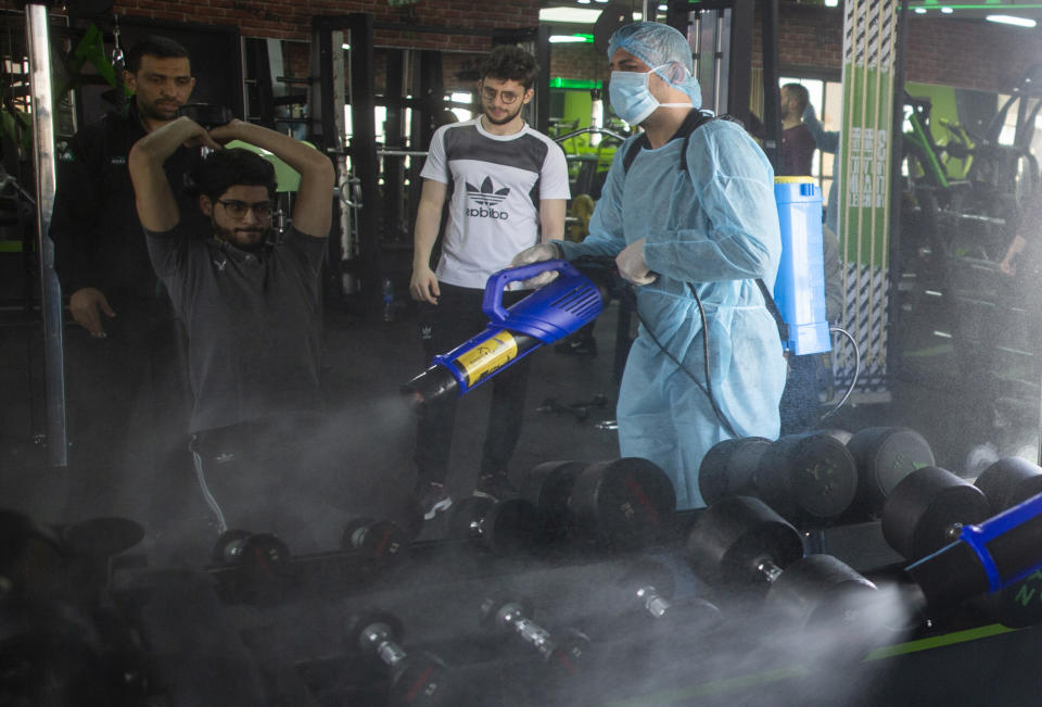 A Palestinian health worker sprays disinfectant as a precaution against the coronavirus in a gymnasium in Gaza City, Sunday, March 15, 2020. (AP Photo/Khalil Hamra)