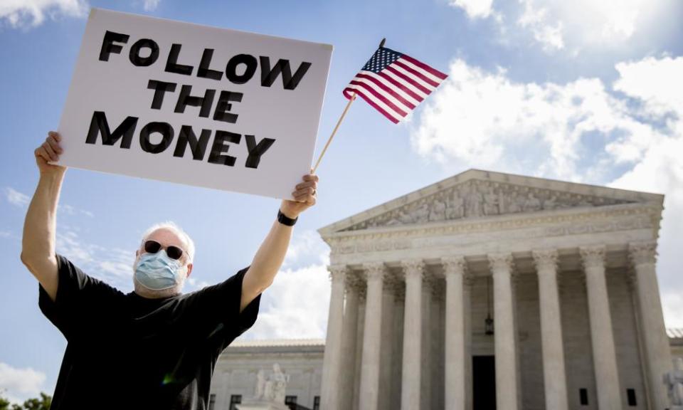 Bill Christeson holds up a sign that reads ‘Follow the Money’ outside the supreme court as it issued an initial ruling on the release of Donald Trump’s tax returns last July.