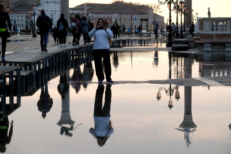 FILE PHOTO: FILE PHOTO: A woman takes a picture in a flooded St. Mark's Square during seasonal high water in Venice