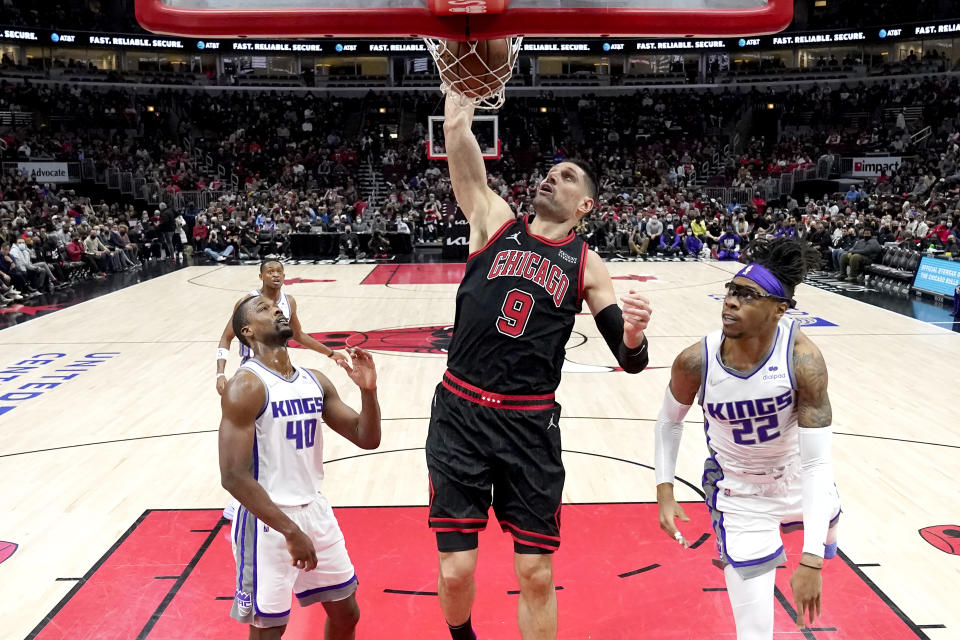 Chicago Bulls' Nikola Vucevic (9) dunks between Sacramento Kings' Harrison Barnes, left, and Richaun Holmes during the first half of an NBA basketball game Wednesday, Feb. 16, 2022, in Chicago. (AP Photo/Charles Rex Arbogast)