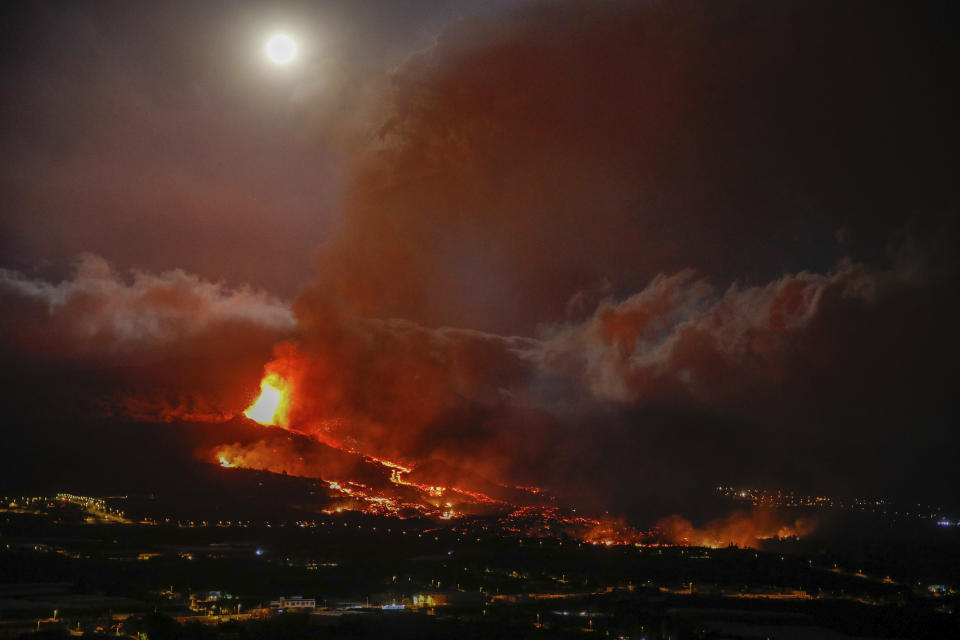 Lava erupts from a volcano near El Paso on the island of La Palma in the Canaries, Spain, Monday Sept. 20, 2021. Giant rivers of lava are tumbling slowly but relentlessly toward the sea after a volcano, seen in backround, erupted on a Spanish island off northwest Africa. The lava is destroying everything in its path but prompt evacuations helped avoid casualties after Sunday's eruption. (Kike Rincon, Europa Press via AP)