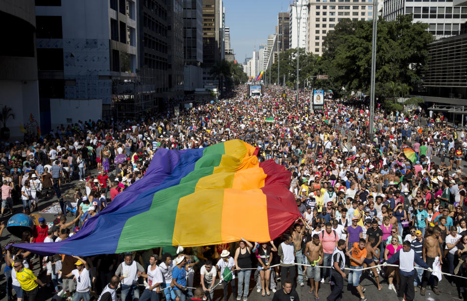 Participants carry a rainbow flag as thousands march during the annual Gay Pride Parade in Sao Paulo, Brazil, Sunday, May 4, 2014. Gay rights advocates are calling for a Brazilian law against discrimination as they gather by the hundreds of thousands in Sao Paulo for one of the world's largest gay pride parades. (AP Photo/Andre Penner)