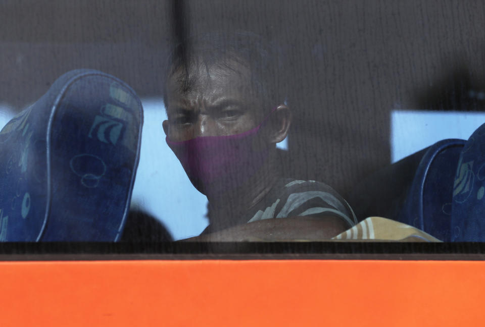 A bus passenger wears mask at a checkpoint during the imposition of large-scale restriction to curb the spread of the new coronavirus outbreak in toll road Cikarang, West Java, Indonesia, Friday, April 24, 2020. Indonesia is suspending passenger flights and rail service as it restricts people in the world's most populous Muslim nation from traveling to their hometowns during the Islamic holy month of Ramadan because of the coronavirus outbreak.(AP Photo/Achmad Ibrahim)
