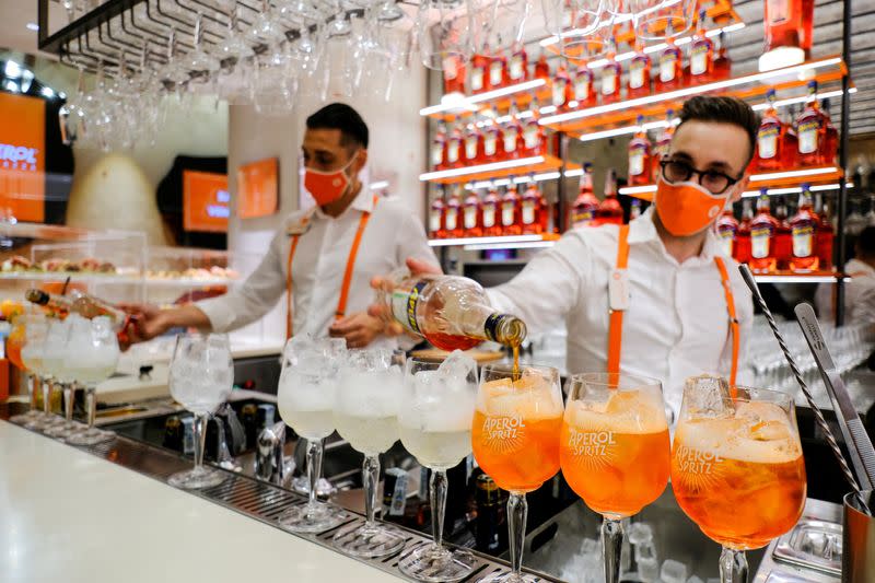 FILE PHOTO: Bartenders pour drinks at a Campari inauguration of a new brand house for Aperol, its best-selling beverage, in Venice, Italy