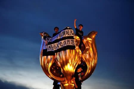 Pro-democracy activists chant slogans on the Golden Bauhinia, a gift from China at the 1997 handover, during a protest a day before Chinese President Xi Jinping is due to arrive for the celebrations, in Hong Kong, China June 28, 2017. REUTERS/Damir Sagolj