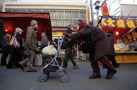 An elderly woman pushes a walking aid as she walks on a street at Tokyo's Sugamo district, an area popular among the Japanese elderly, in Tokyo January 14, 2015. REUTERS/Toru Hanai