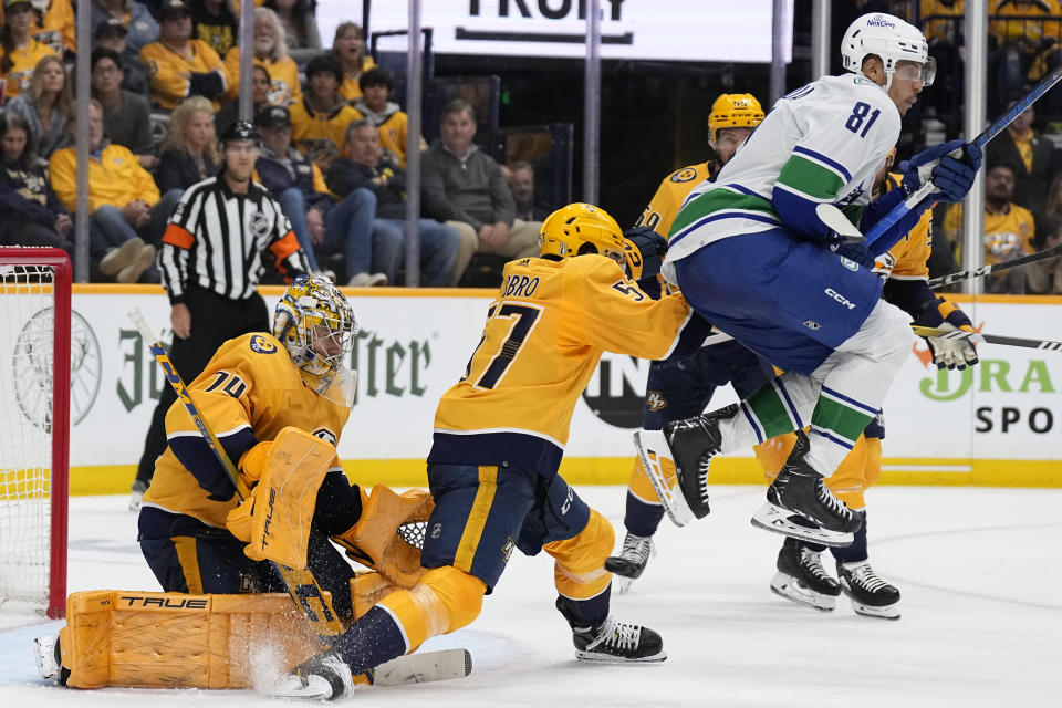 Nashville Predators defenseman Dante Fabbro (57) and goaltender Juuse Saros (74) block a shot on goal as Vancouver Canucks center Dakota Joshua (81) leaps over the puck during the third period in Game 6 of an NHL hockey Stanley Cup first-round playoff series Friday, May 3, 2024, in Nashville, Tenn. The Canucks won 1-0. (AP Photo/George Walker IV)