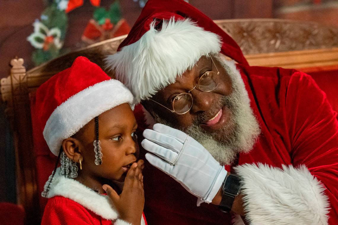 Nai’lah McCullers, 4, whispers her Christmas list while having her photograph taken with Santa Claus, aka Joe Griffin, or Santa Joe, at the Hayti Heritage Center in Durham Wednesday, Dec. 21, 2022.