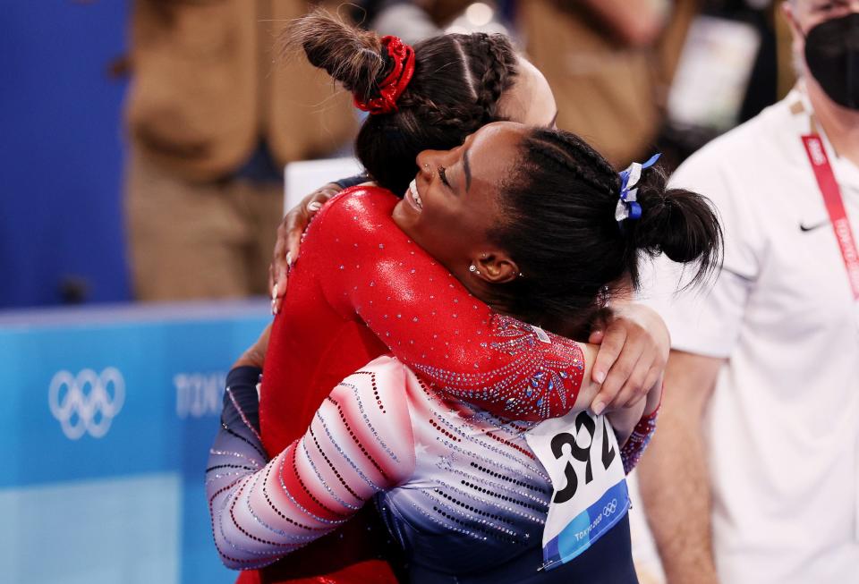 Simone Biles hugs Suni Lee during the balance beam final at the Tokyo Olympics.