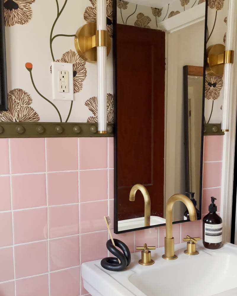 bathroom with pink tile, arched mirror, botanical wallpaper, and gold hardware/accents after remodel