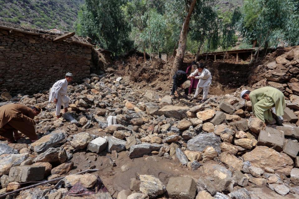 Afghan villagers clean debris next to their houses damaged in flash floods in Watapur district of Kunar province (AFP via Getty Images)