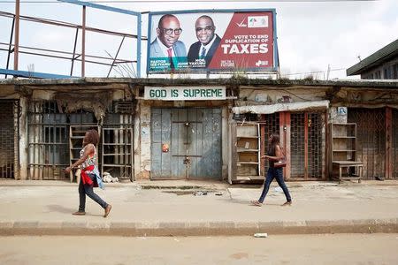 People walk past closed shops during the coronation of Oba of Benin, Eheneden Erediauwa, near the Oba's palace in Benin city, Nigeria October 20, 2016.REUTERS/Akintunde Akinleye