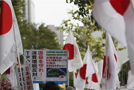 A member of the nationalist movement "Ganbare Nippon" holding a placard of disputed islands known as Senkaku in Japan and Diaoyu in China, walks among Japanese national flags during a rally in Tokyo September 11, 2013, on the day of one year anniversary of Japanese government signed contract to buy islands disputed with China from a private owner. REUTERS/Toru Hanai