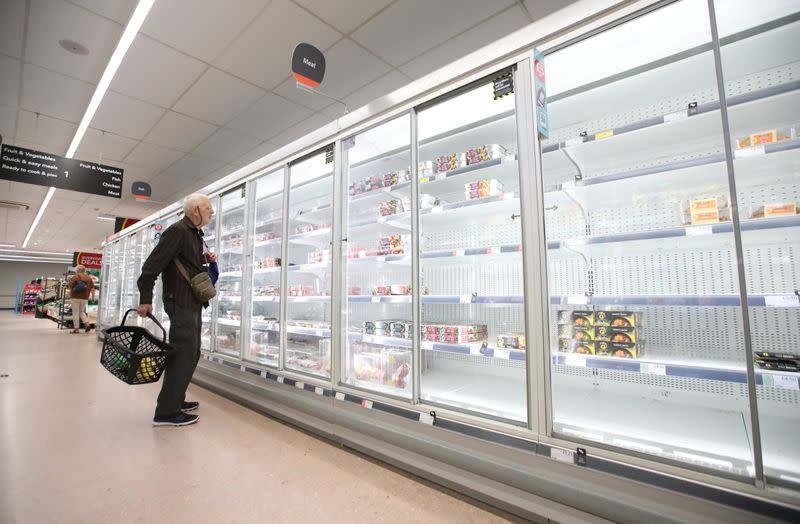 A shopper looks at produce and empty shelves of the meat aisle in Co-Op supermarket, Harpenden