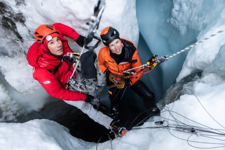 Two climbers attempt to climb a glacier.