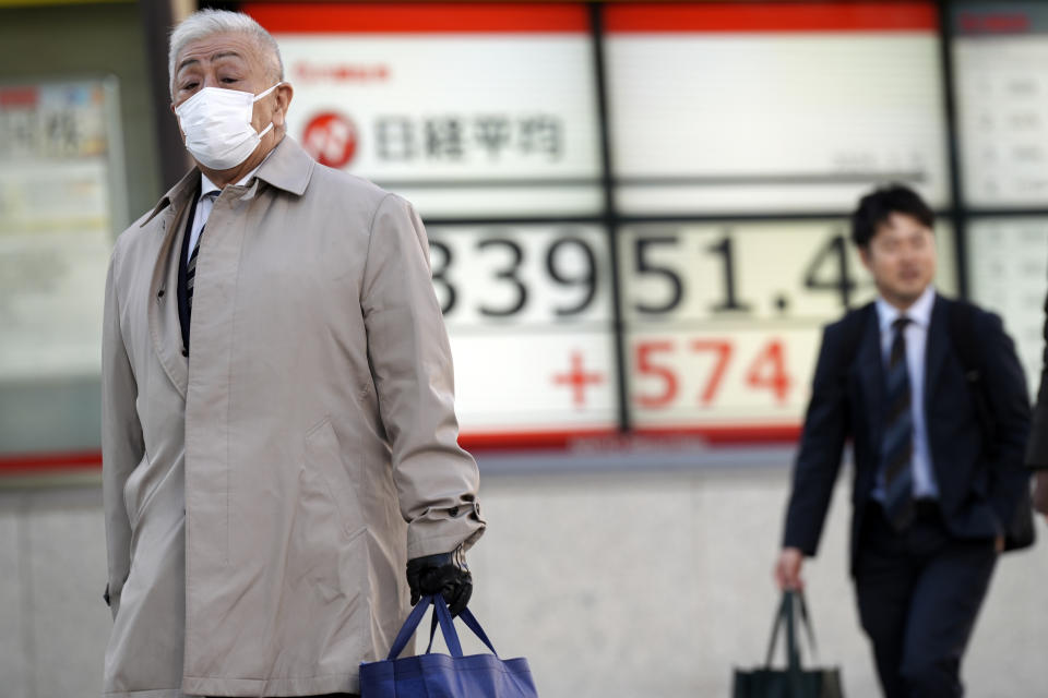 People walk in front of an electronic stock board showing Japan's Nikkei 225 index at a securities firm Tuesday, Jan. 9, 2024, in Tokyo. (AP Photo/Eugene Hoshiko)