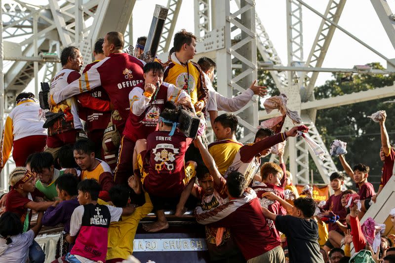 Filipino devotees attempt to climb and touch the Black Nazarene during the annual procession celebrating its feast day in Manila