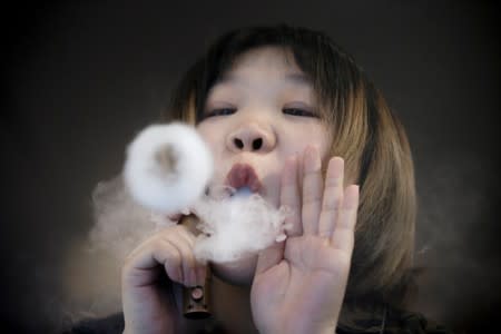 FILE PHOTO: Saleswoman demonstrates vaping at Vape Shop in Beijing