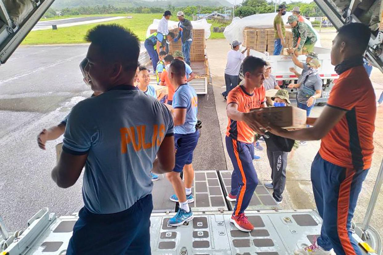 police and coast guard personnel unloading relief supplies from an air force C-130 transport plane at Basco airport, Batanes province (Tactical Operations Group-Philip)