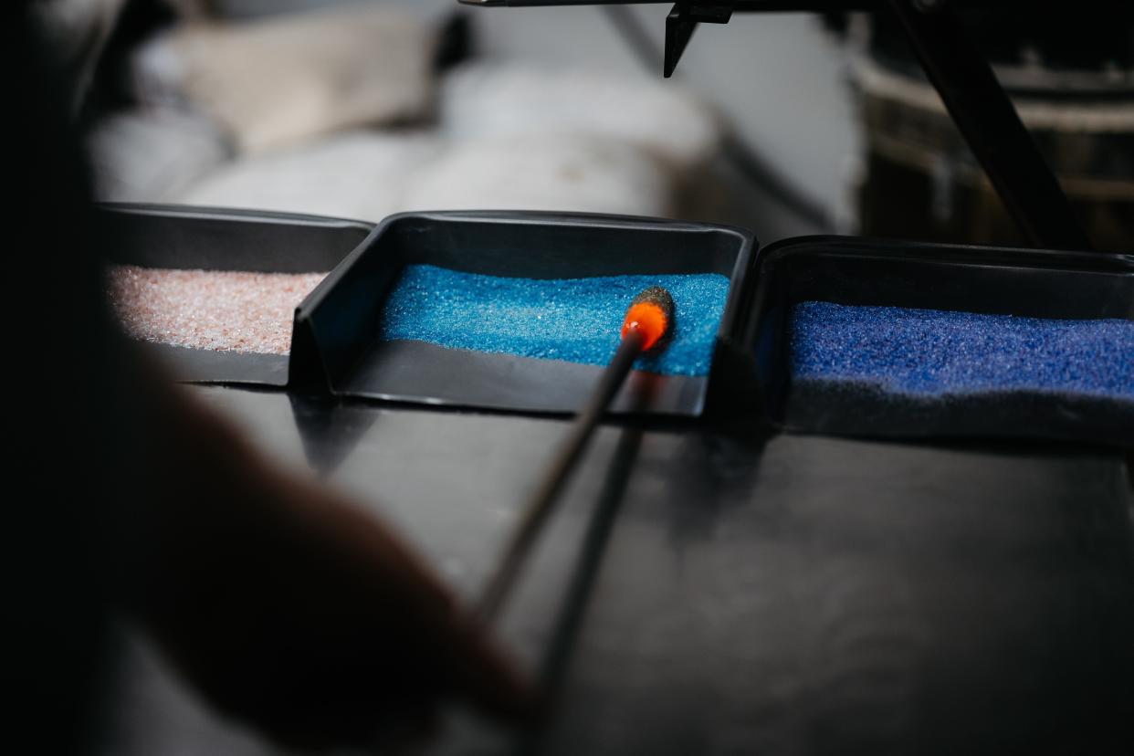 Eric Minton rolls the start of his clear glass egg in colored frit to give it a unique pattern.