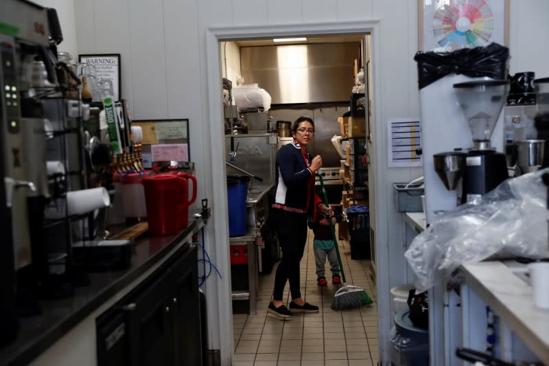 Christina Morales, a line cook of two years at Farley’s East cafe that closed due to the financial crisis caused by the coronavirus disease (COVID-19), cleans with her son Pablo, 2, at the cafe in Oakland