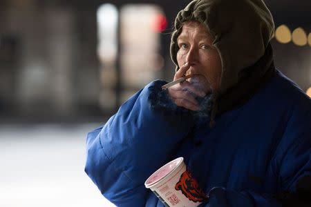 Teresa Sigerson, 51, pauses to smoke while panhandling near the overpass that she resides under in Chicago, December 4, 2014. Sigerson has been living under the overpass for 3 years. REUTERS/Andrew Nelles