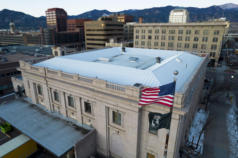 In this aerial image taken with a drone, an American flag and prisoner-of-war/missing-in-action flag fly over buildings in downtown Colorado Springs, Colo, Wednesday, Nov. 23, 2022. With a growing and diversifying population, the city nestled at the foothills of the Rockies is a patchwork of disparate social and cultural fabrics. But last weekend’s shooting has raised uneasy questions about the lasting legacy of cultural conflicts that caught fire decades ago and gave Colorado Springs a reputation as a cauldron of religion-infused conservatism, where LGBTQ people didn't fit in with the most vocal community leaders' idea of family values (AP Photo/Brittany Peterson)