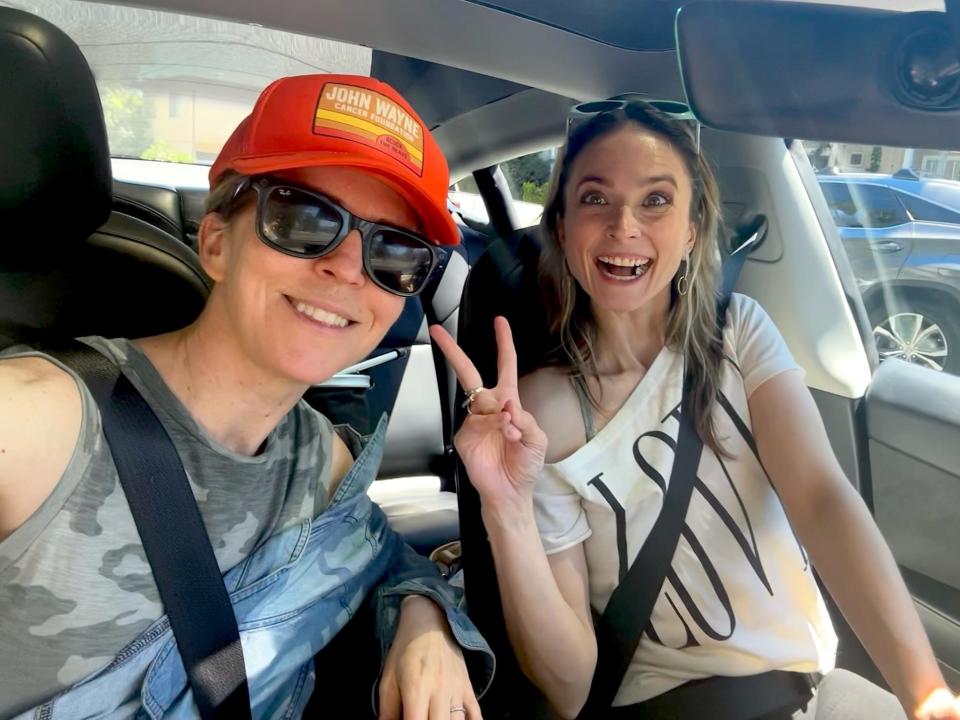 Two women smiling for a selfie inside a Tesla.
