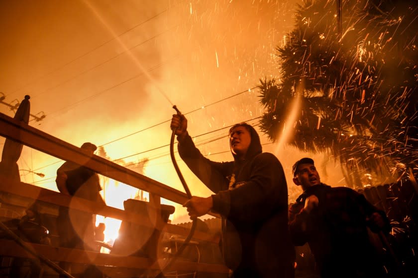 VENTURA, CALIF. -- TUESDAY, DECEMBER 5, 2017: Brandon Baker, center and Prescott McKenzie, right, take cover from the flying embers during a brush fire in Ventura, Calif., on Dec. 5, 2017. (Marcus Yam / Los Angeles Times)