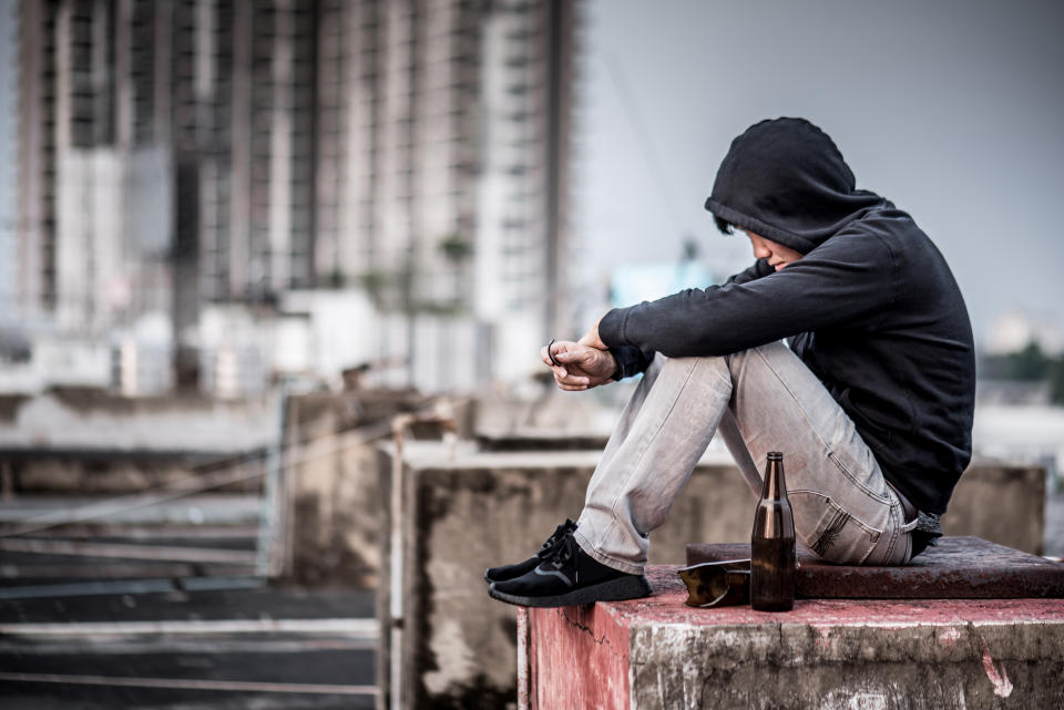 Mystery man in hoody jacket, sitting and hugs his knees up with an empty and broken bottle in abandoned building. depression self destruction suicidal addicts drug, Major depressive disorder concept