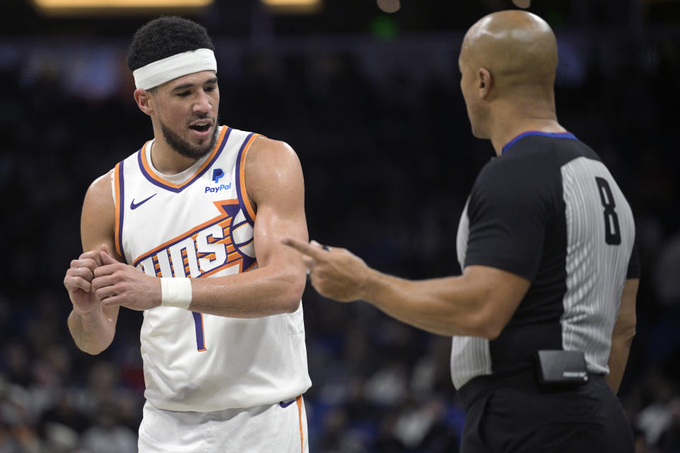 Phoenix Suns guard Devin Booker (1) argues a call with official Marc Davis (8) during the first half of an NBA basketball game against the Orlando Magic, Sunday, Jan. 28, 2024, in Orlando, Fla. (AP Photo/Phelan M. Ebenhack)