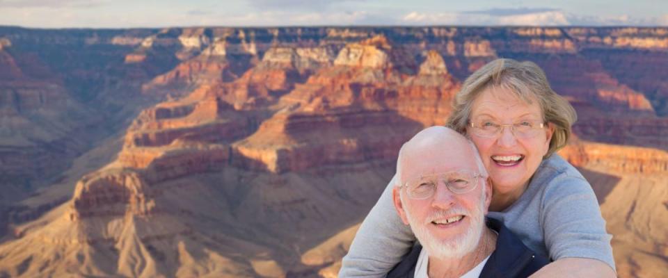 Happy, Hugging Senior Couple Posing on the Edge of The Grand Canyon.