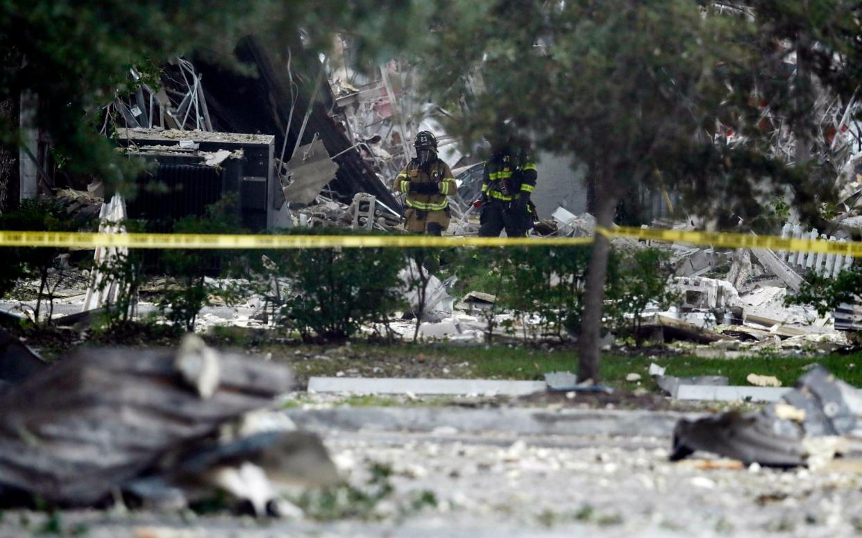 Firefighters walk through the remains of a building after an explosion - AP