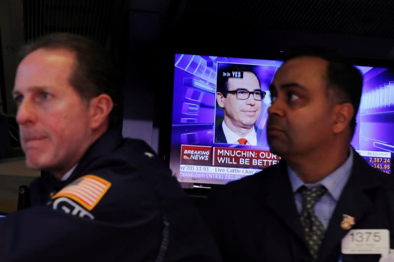 Traders work as a television shows U.S. Treasury Secretary Steven Mnuchin speaking at the New York Stock Exchange as markets continue to react to the coronavirus disease (COVID-19) at the NYSE in New York